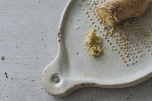Japanese ceramic ginger grater with fresh ginger on a weathered work surface